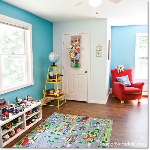 boy room with shelf full of toys, stuffed animals, globe and big red chair and rug