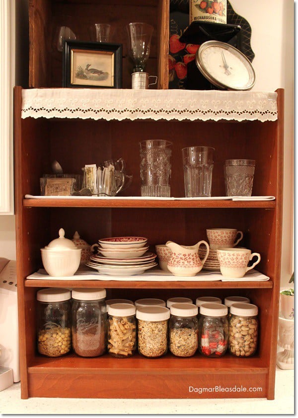 shelf on counter with glasses an mason jars with cereal