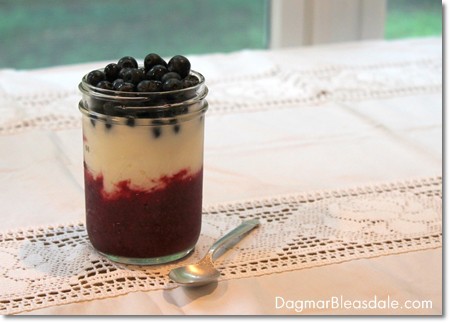 yogurt and berries in jar on table, silver spoon
