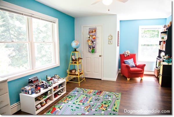 boy's bedroom with large windows, chair, bookshelf, toys