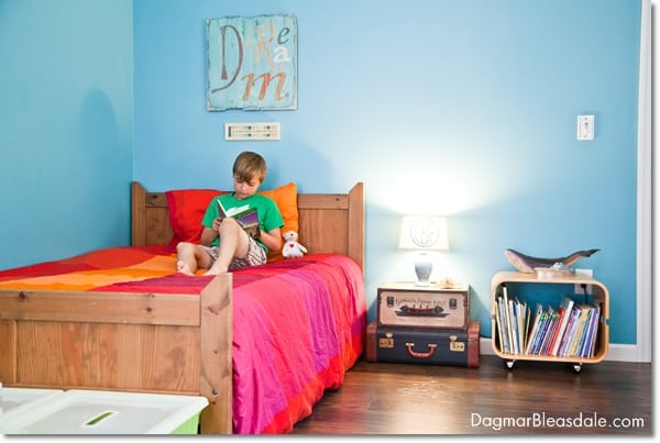 boy reading on bed in kid's room, suitcase bedsidee table