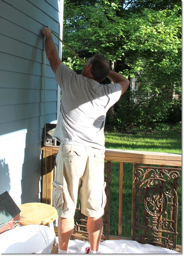 man measuring wall on porch