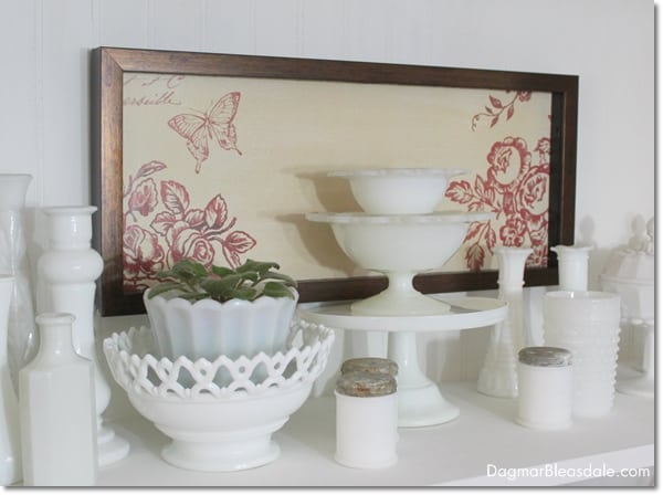 framed picture with flowers and milk glass vases and items on shelf