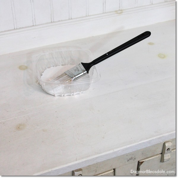 paint brush and white paint in plastic dish on hutch