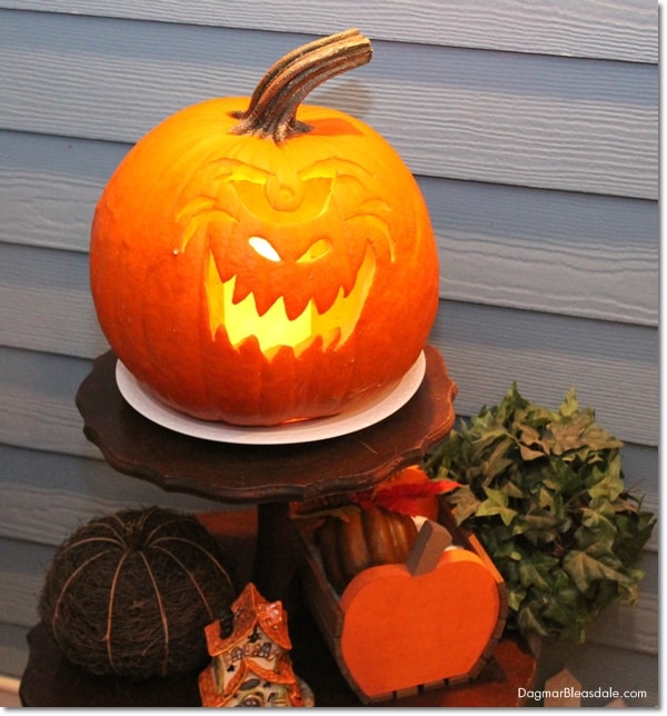 carved pumpkin with candle on small table