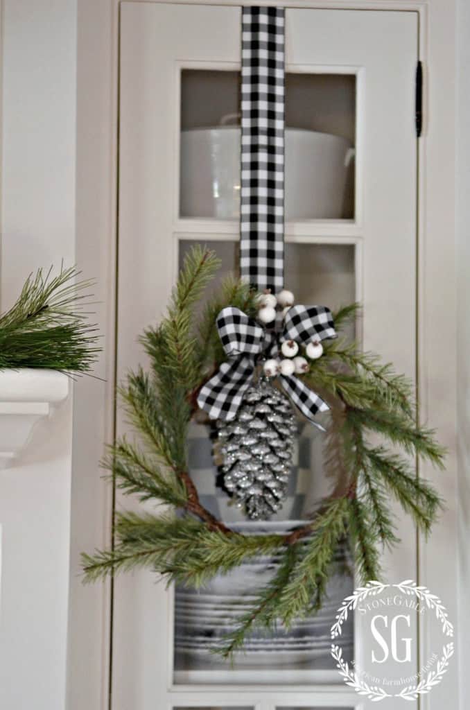 little green wreath with ribbon hung on kitchen cabinet
