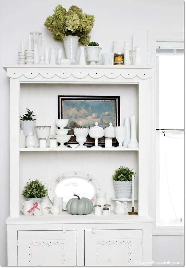 hutch with vintage milk glass collection and oil painting and plants