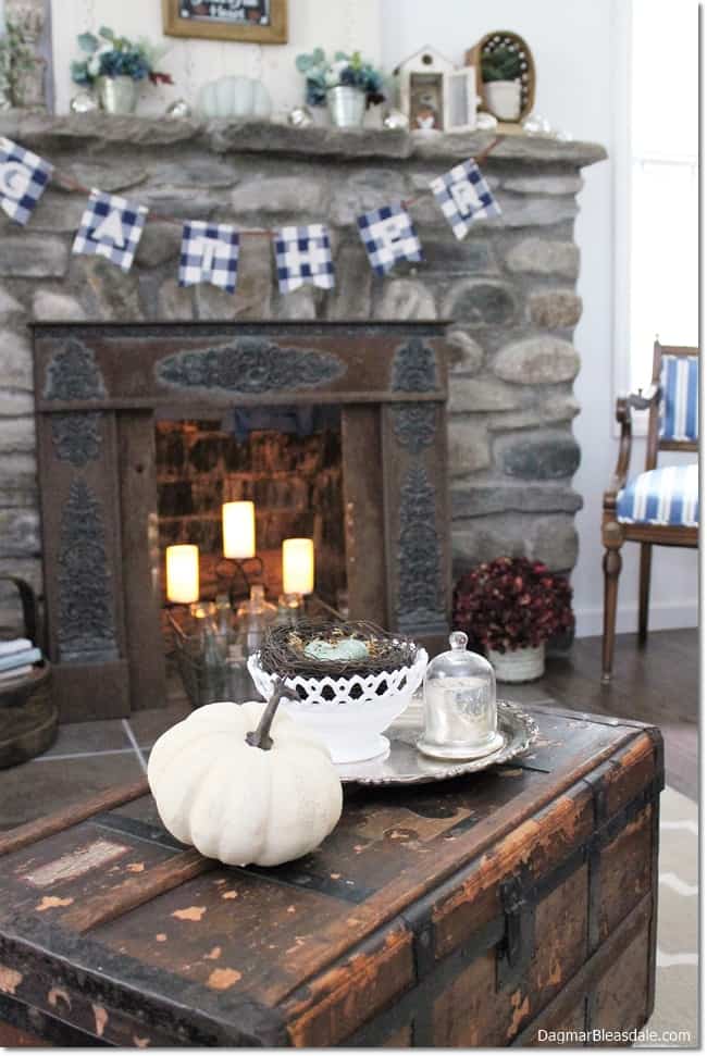 white living room with stone fireplace, banner, and fall decor