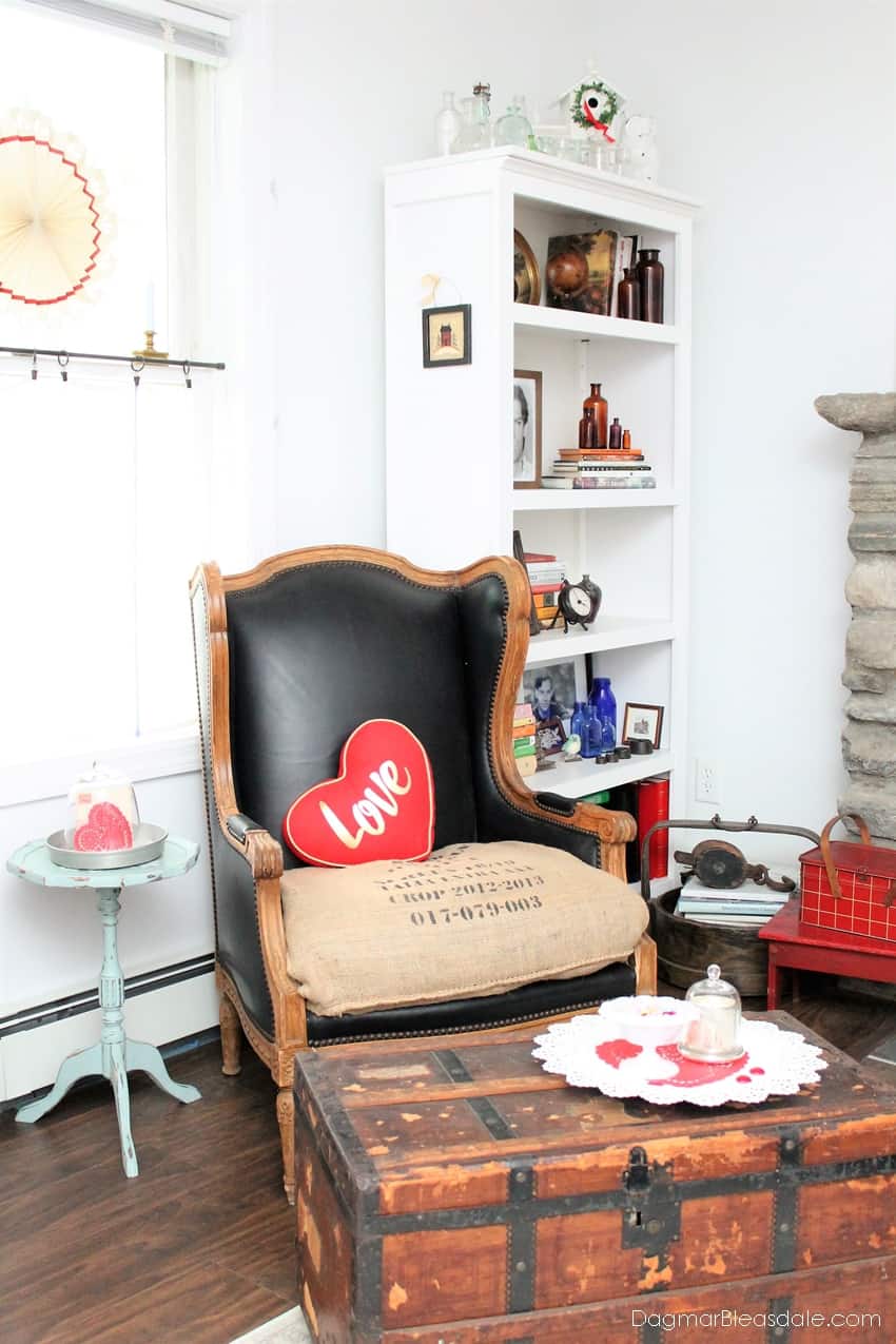 Heart-shaped pillow on chair, trunk and side table decorated for Valentine's Day