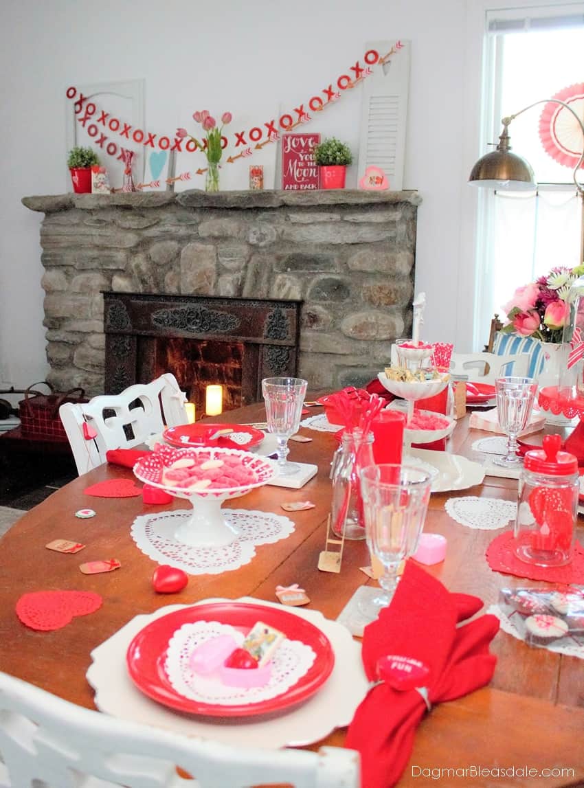 table decorated for Valentine's Day with many red items, banners over fireplace