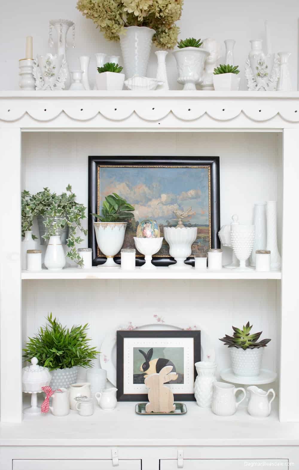 milk glass collection in white dresser with plants and pictures