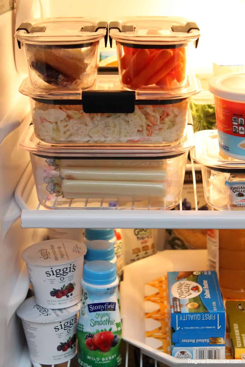 clear organizing containers filled with cheese, carrots, salad on fridge shelf