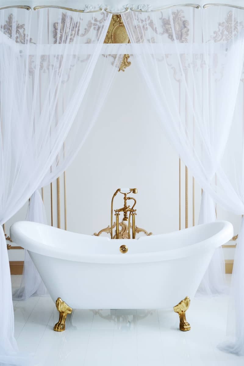clawfoot tub with gold feet and white cutrains