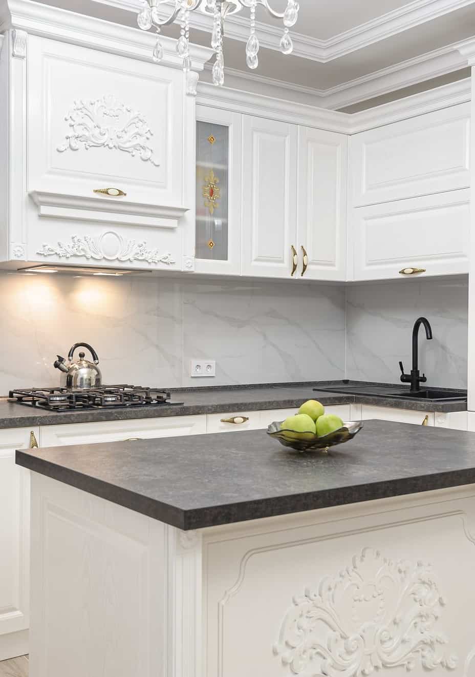 white kitchen cabinets, gray counters, chandelier