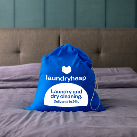 Blue laundry bag on bed, headboard in background