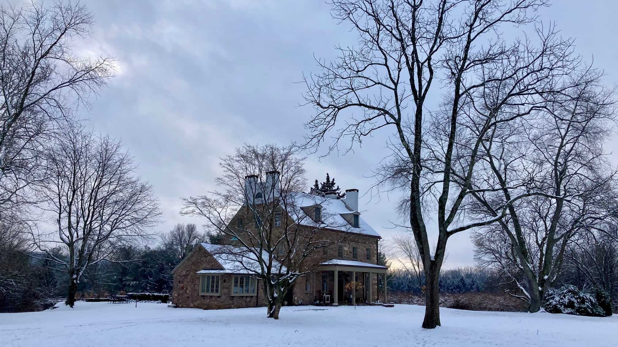 stone manor house in Bucks County, PA stone manor house and trees in the winter with snow